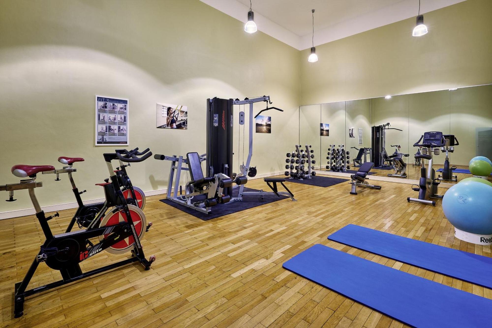 Отель The Westin Grand Берлин Экстерьер фото The photo depicts a fitness or workout room. It features various exercise equipment, including:

- A stationary bike on the left.
- A multi-gym machine in the center, designed for different strength training exercises.
- A set of free weights organiz